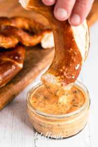 Aztec Sauce - spicy dipping sauce in glass jar with pretzel dipping into it