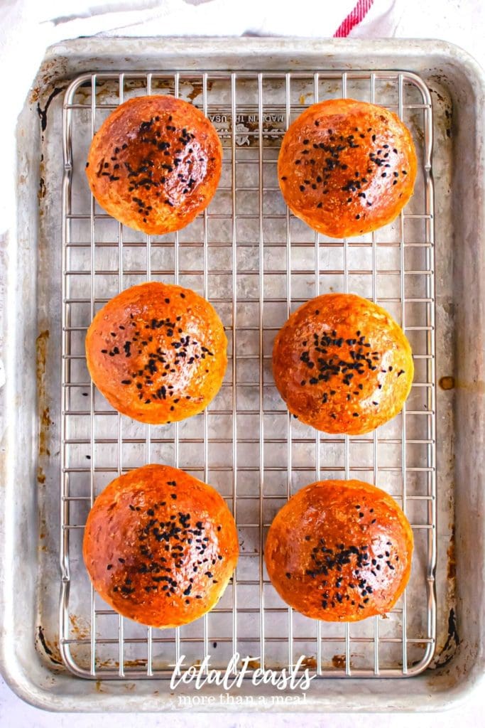 overhead shot of six burger buns on a baking tray