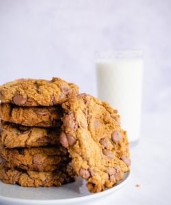 side shot of stack of brown butter chocolate chip cookies with glass on milk