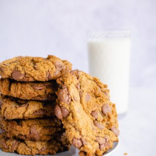 side shot of stack of brown butter chocolate chip cookies with glass on milk