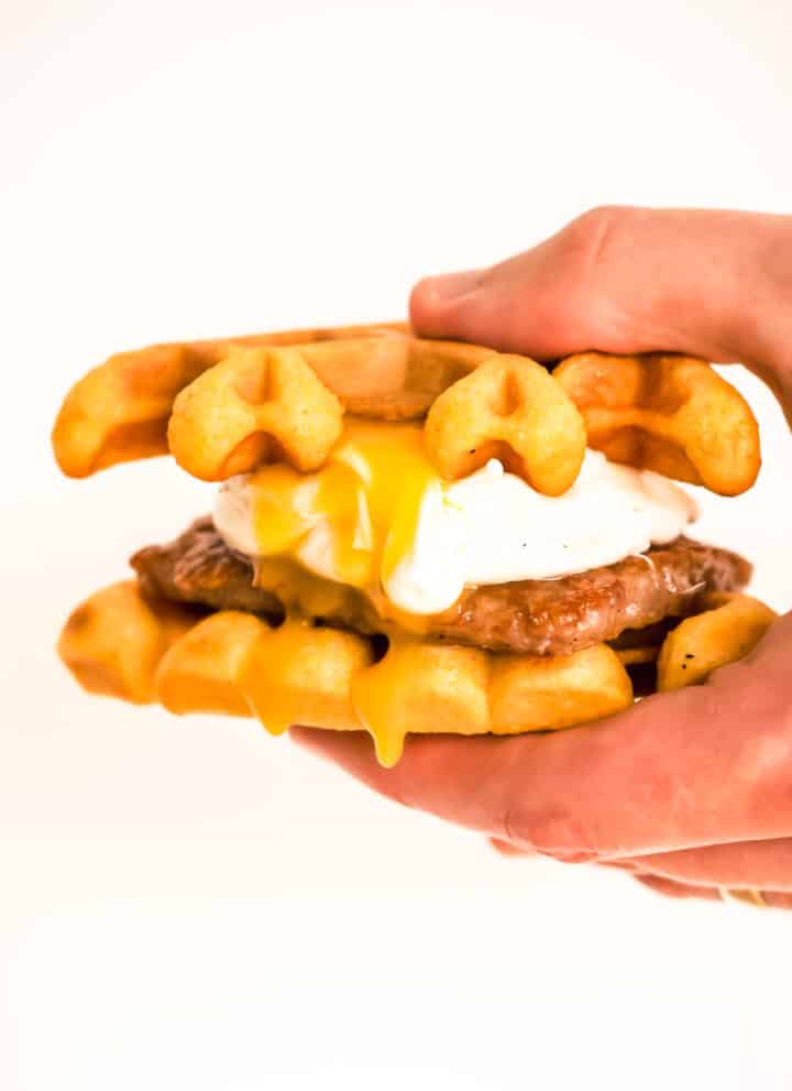 southern cornmeal waffles sandwich with poached egg and sausage patty